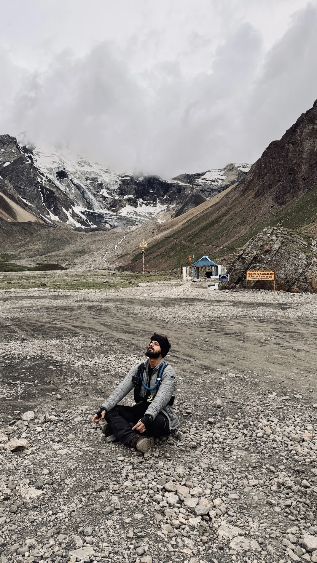 Shubham sitting on rocky ground surrounded by mountain slopes